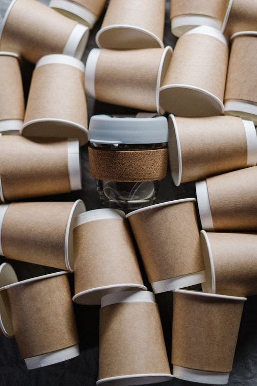 Kraft paper cups arranged around a reusable coffee cup